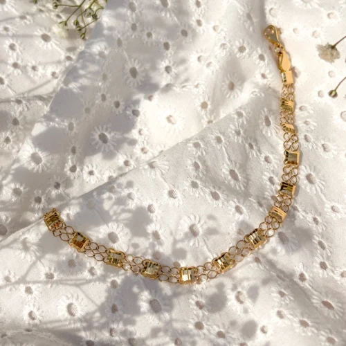 Złota bransoleta ozdobiona lśniącymi elementami