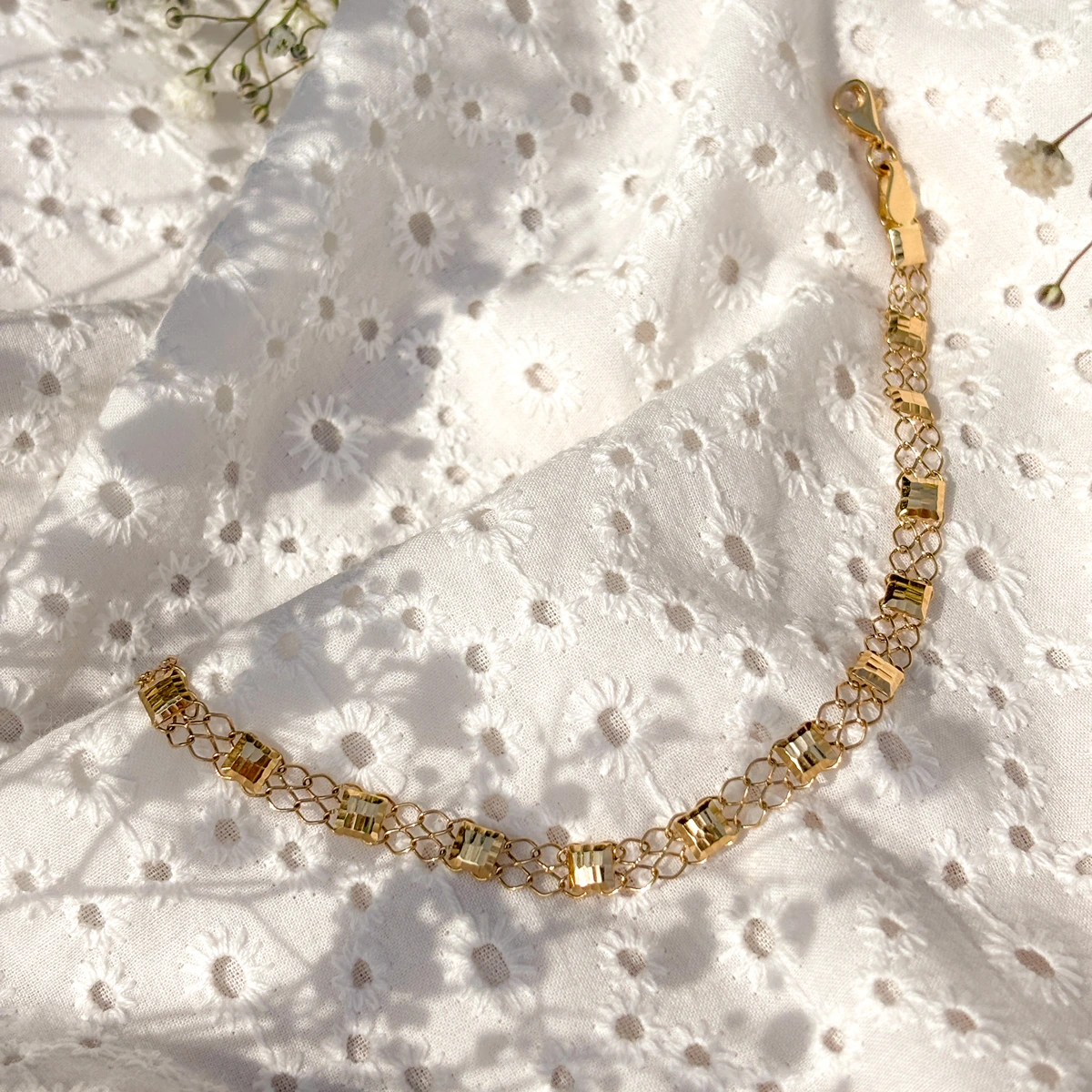 Złota bransoleta ozdobiona lśniącymi elementami