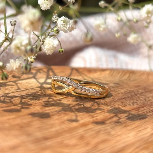 Złoty pierścionek w formie plecionki, ozdobiony cyrkoniami