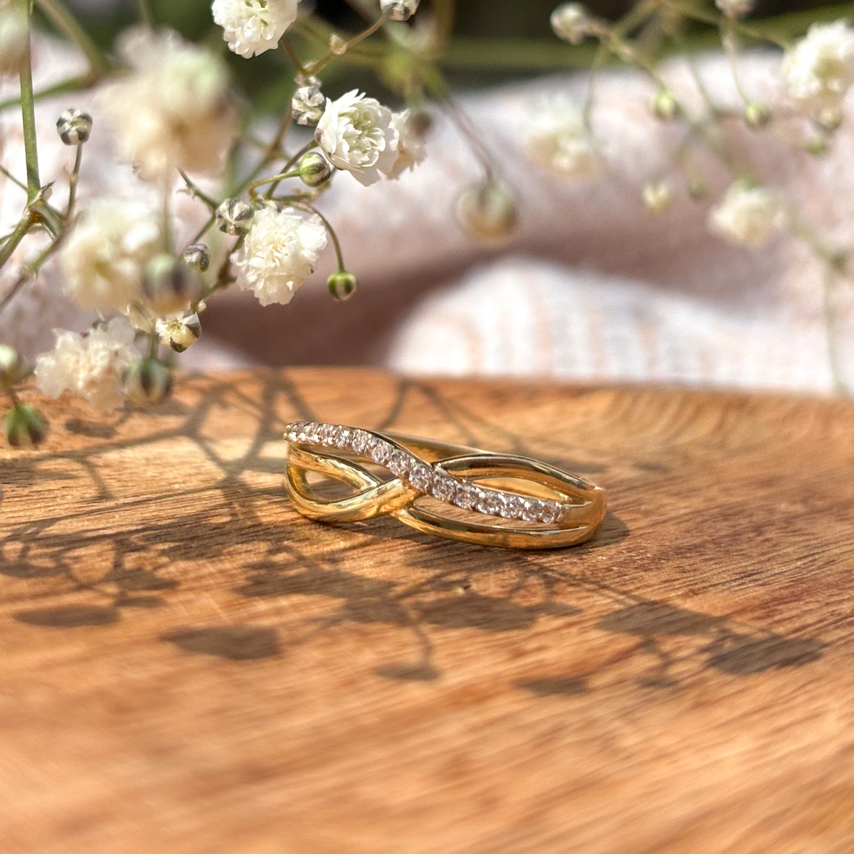 Złoty pierścionek w formie plecionki, ozdobiony cyrkoniami